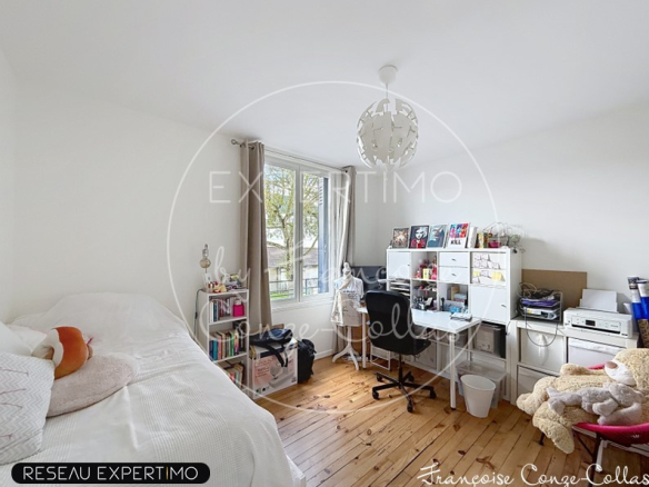 Chambre lumineuse avec un bureau et des rangements, fenêtres donnant sur l'extérieur.