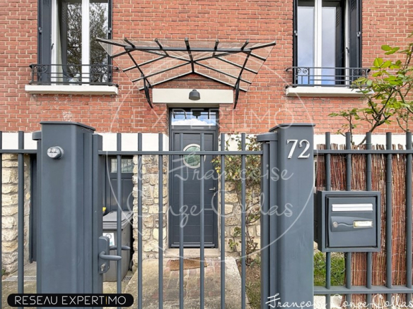 Façade d'une maison en meulière à Issy-les-Moulineaux avec un portail et un auvent.