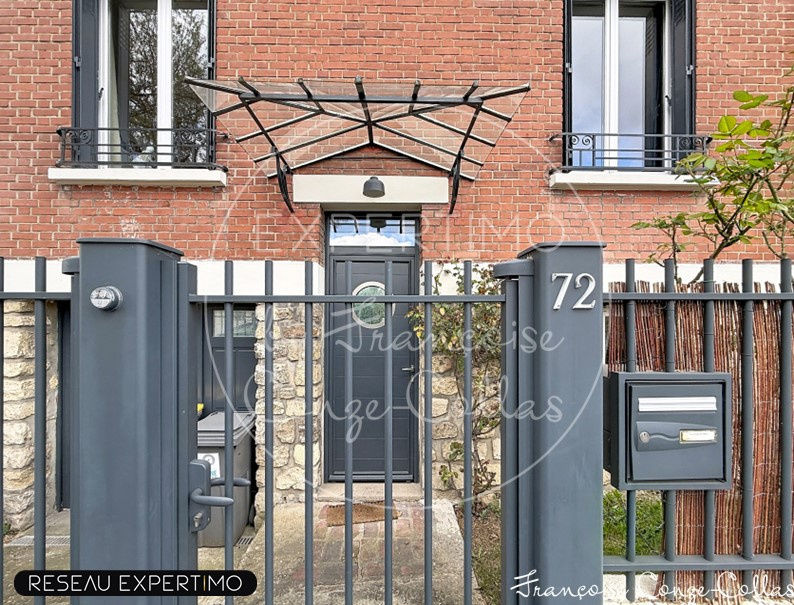 Façade d'une maison en meulière à Issy-les-Moulineaux avec un portail et un auvent.