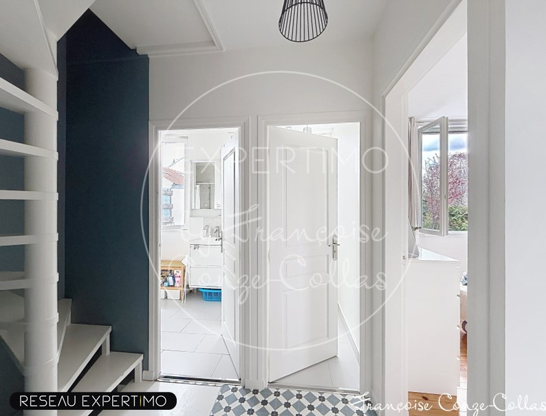 Vue intérieure d'une maison rénovée avec entrée et portes ouvertes sur un espace lumineux.