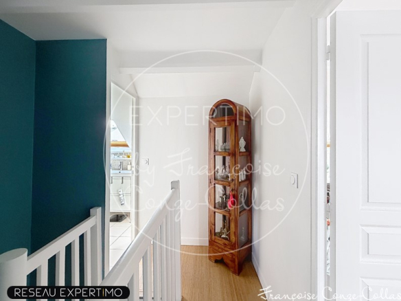 Intérieur d'une maison rénovée avec un couloir lumineux et un meuble ancien en bois.
