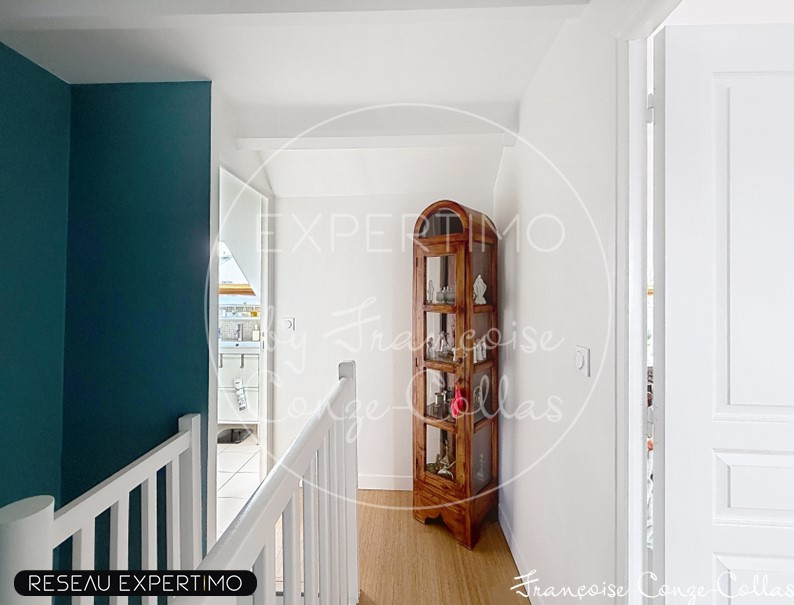 Intérieur d'une maison rénovée avec un couloir lumineux et un meuble ancien en bois.