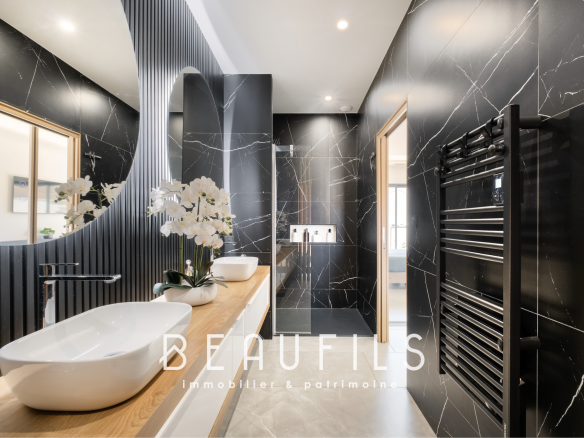 Salle de bain moderne avec murs en marbre noir et double vasque, éclairage naturel