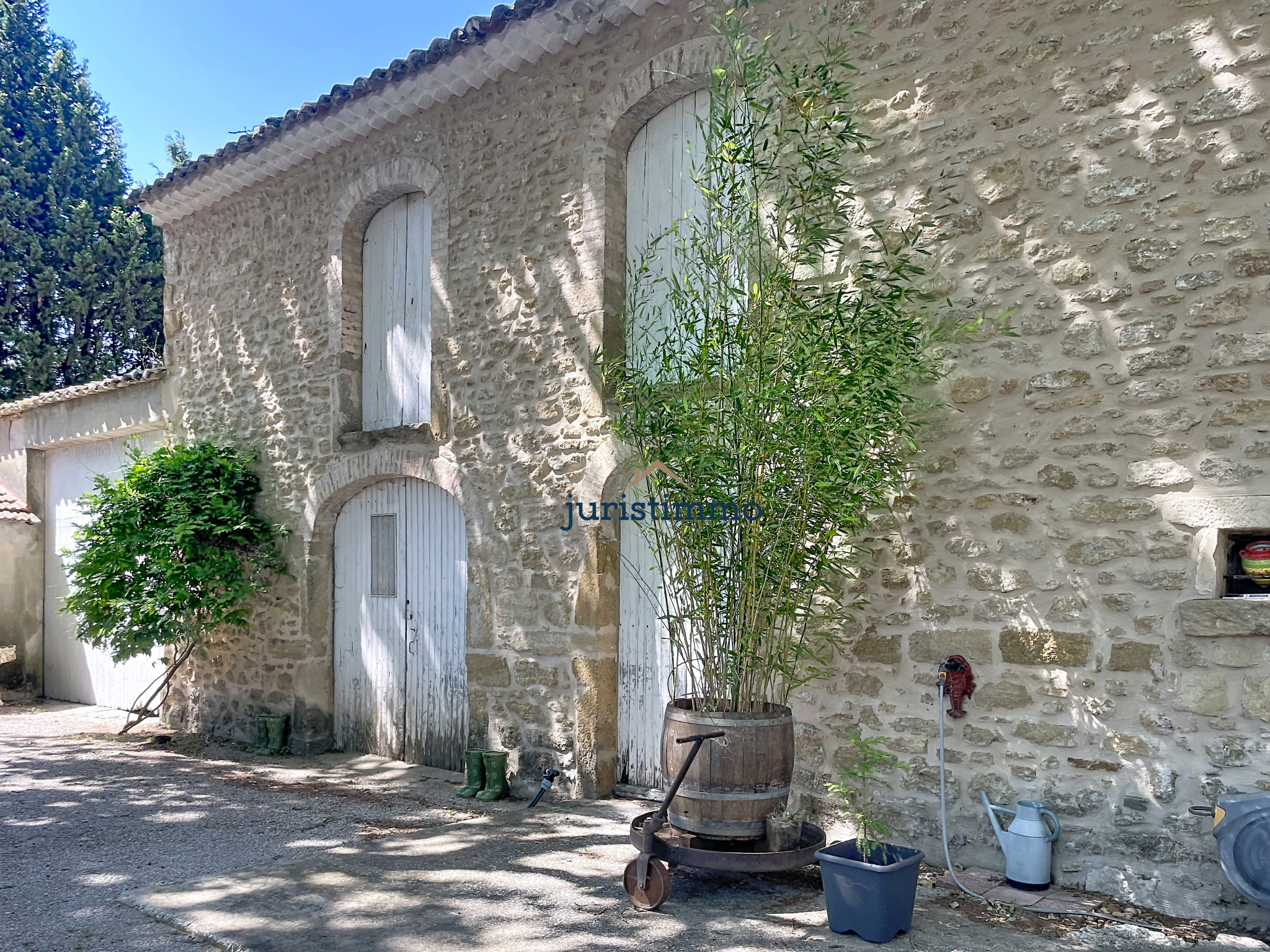 Stone property in Provence Stone building with wooden shutters and surrounding vegetation, located in a wooded park.