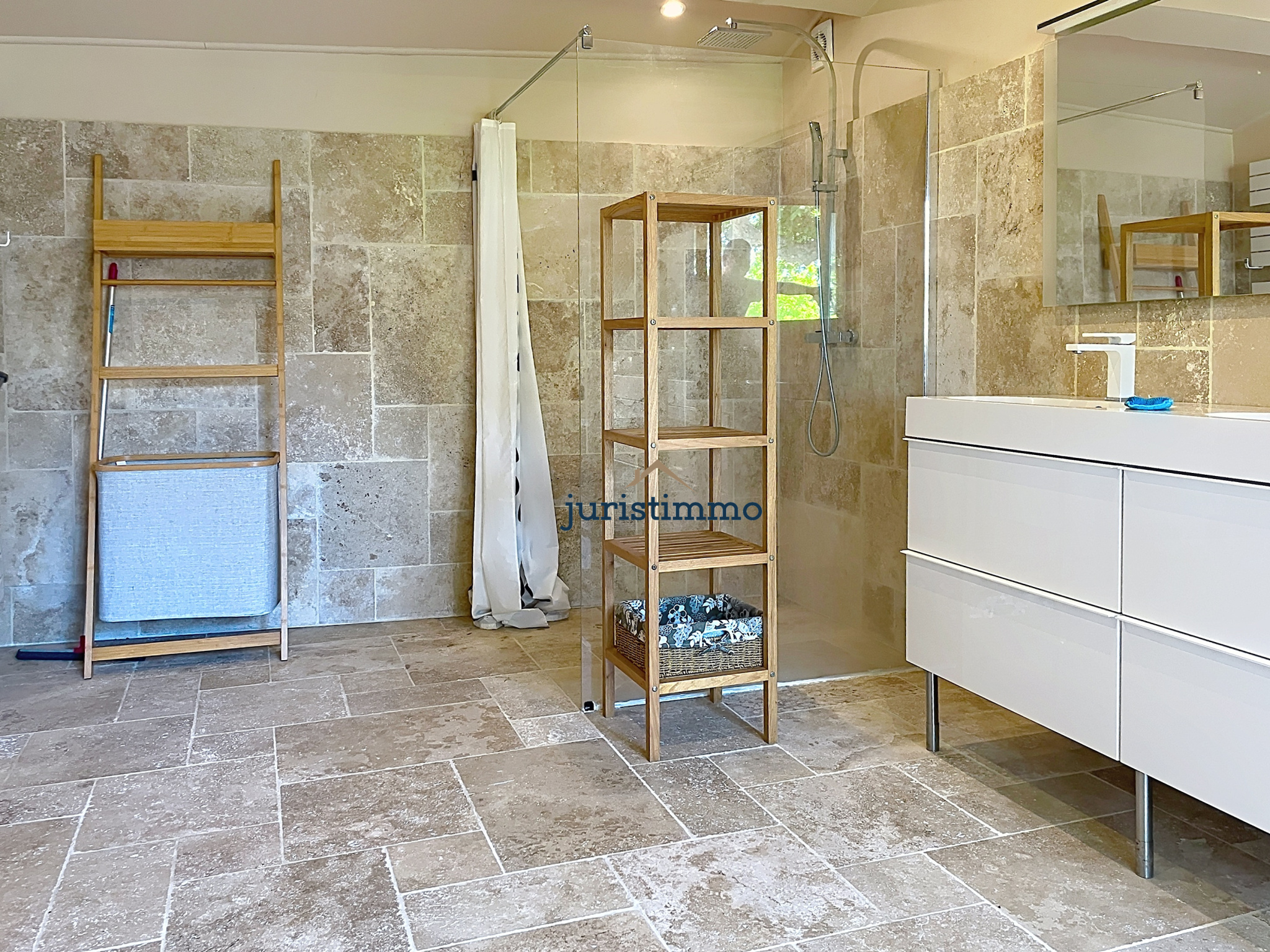 Elegant bathroom Modern bathroom with stone tiles, white vanity unit and wooden shelf.