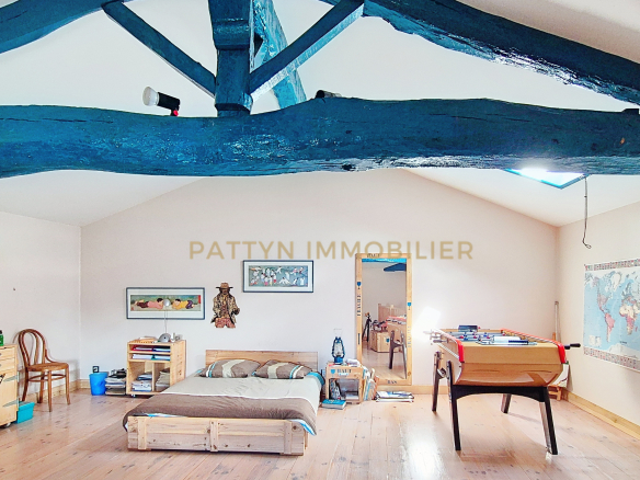 Interior of a house in Tramoyes with exposed beams and a furnished living space.