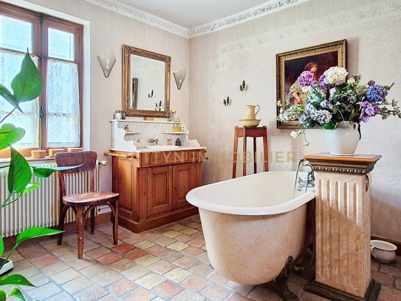 Bathroom with freestanding bathtub, mirror and floral decoration, in a house in Tramoyes.