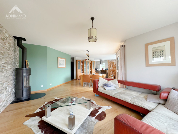 Intérieur d'une maison moderne avec un salon lumineux, un poêle à bois et une salle à manger.