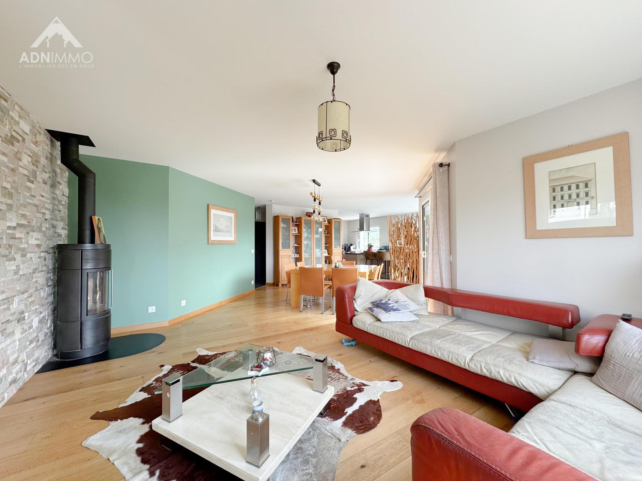 Intérieur d'une maison moderne avec un salon lumineux, un poêle à bois et une salle à manger.