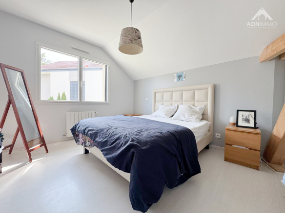 Chambre d'une maison individuelle à Chevry, avec lit double et fenêtre lumineuse.