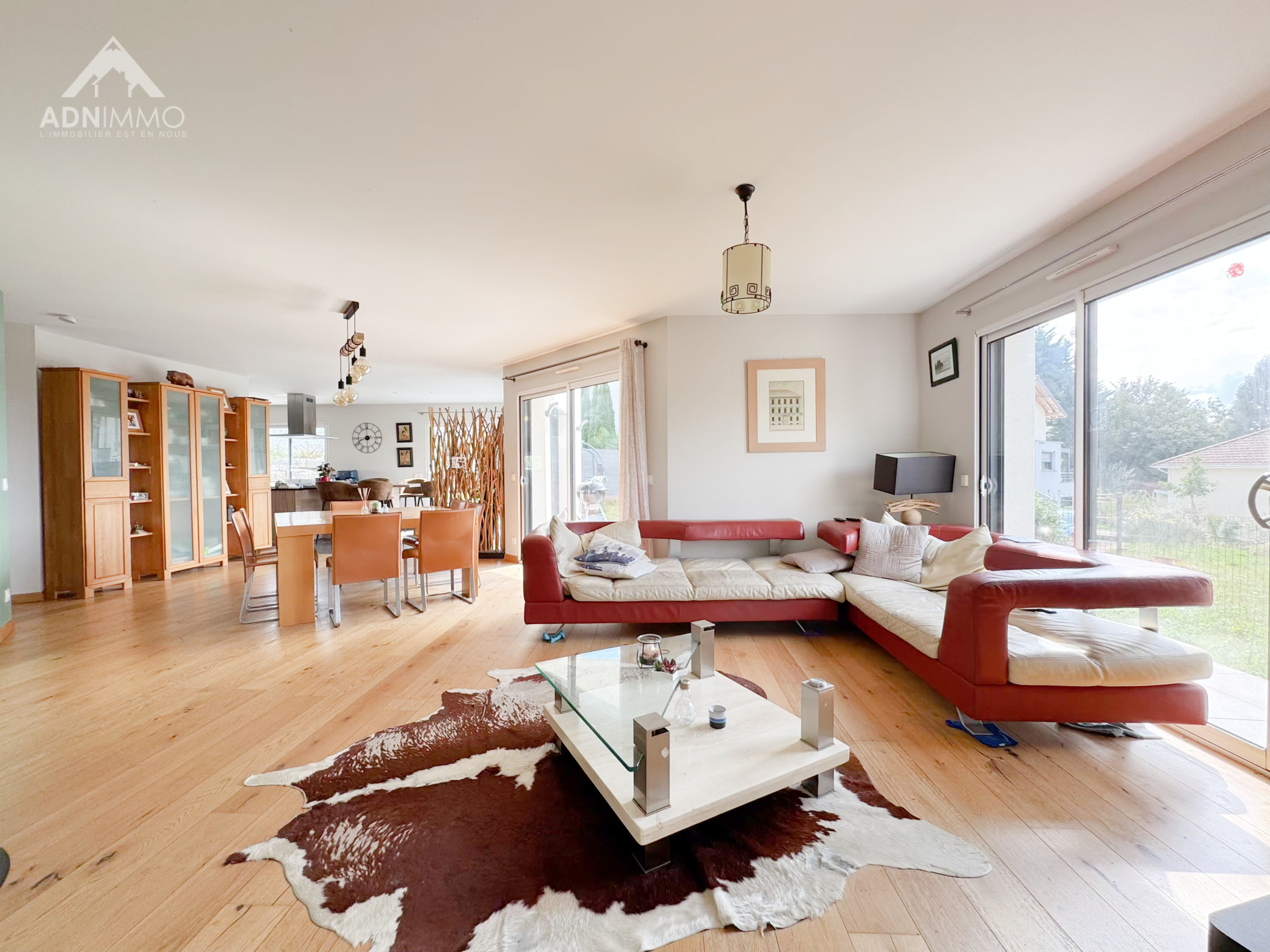Intérieur d'une maison moderne avec un salon lumineux, un coin repas et une cuisine ouverte.