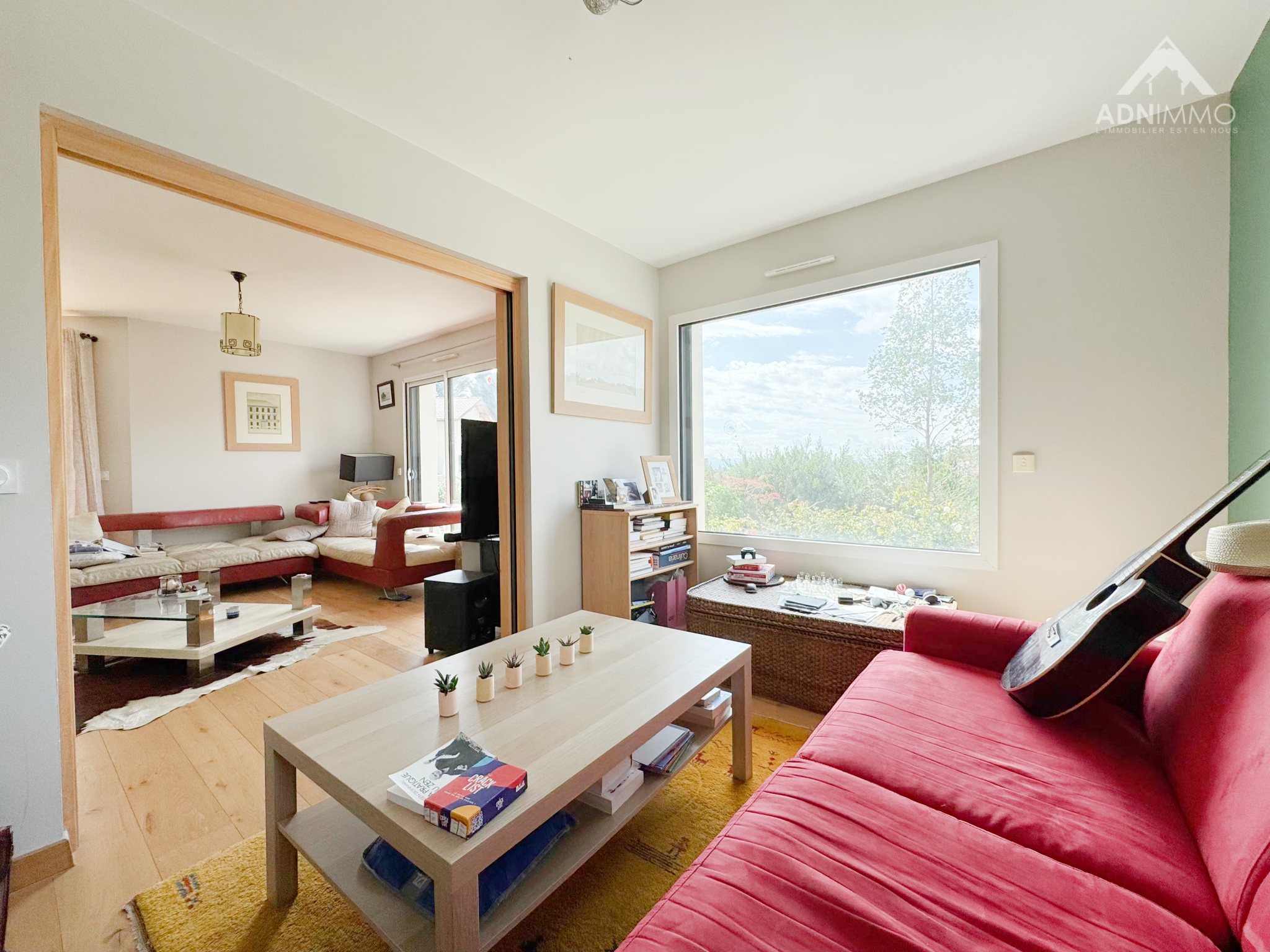 Intérieur d'une maison moderne avec salon lumineux et canapé rouge à Chevry.