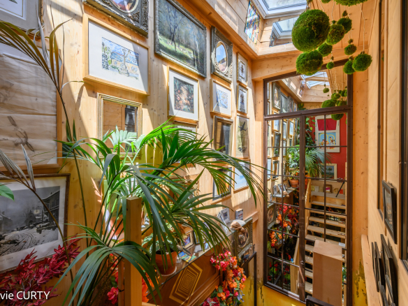 Intérieur d'une maison de caractère avec des plantes et des œuvres d'art accrochées aux murs.