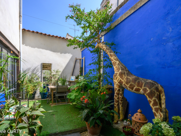 Jardin avec une girafe en décoration et des plantes, maison de caractère à La Rochelle.