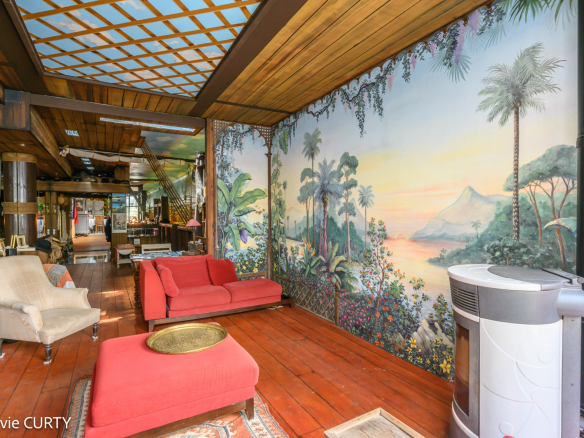 Intérieur d'une maison de caractère avec un grand mur peint et un salon confortable.