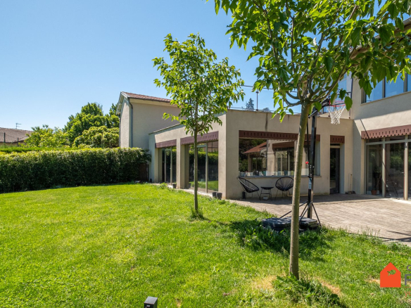 Maison familiale rénovée avec jardin à Saint-Genis-Laval, extension contemporaine et matériaux nobles.