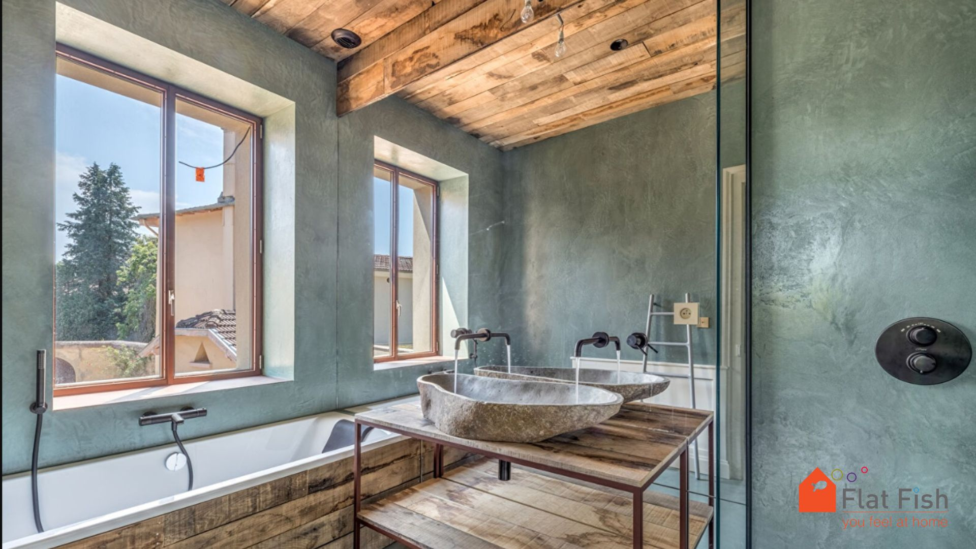 Salle de bain rénovée avec style contemporain Salle de bain moderne avec baignoire et vasques en pierre, murs en béton ciré et fenêtres lumineuses.