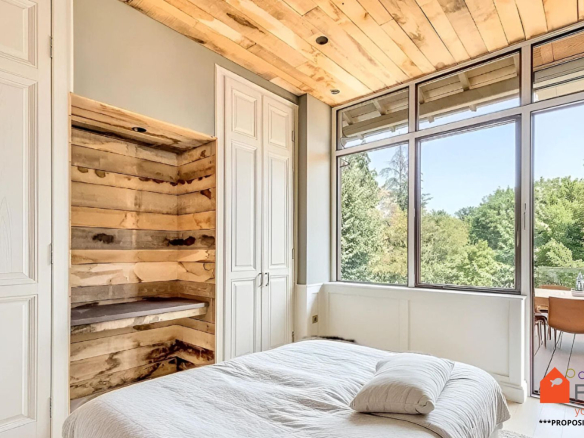 Chambre lumineuse avec vue sur le jardin, murs en bois et lit simple.