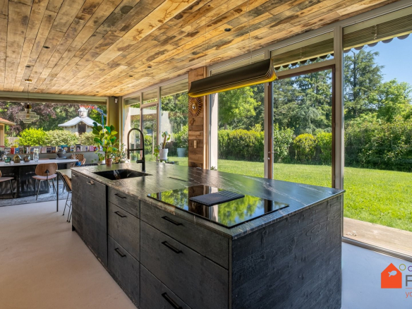 Cuisine moderne avec îlot central et vue sur jardin dans une maison rénovée à Saint-Genis-Laval.