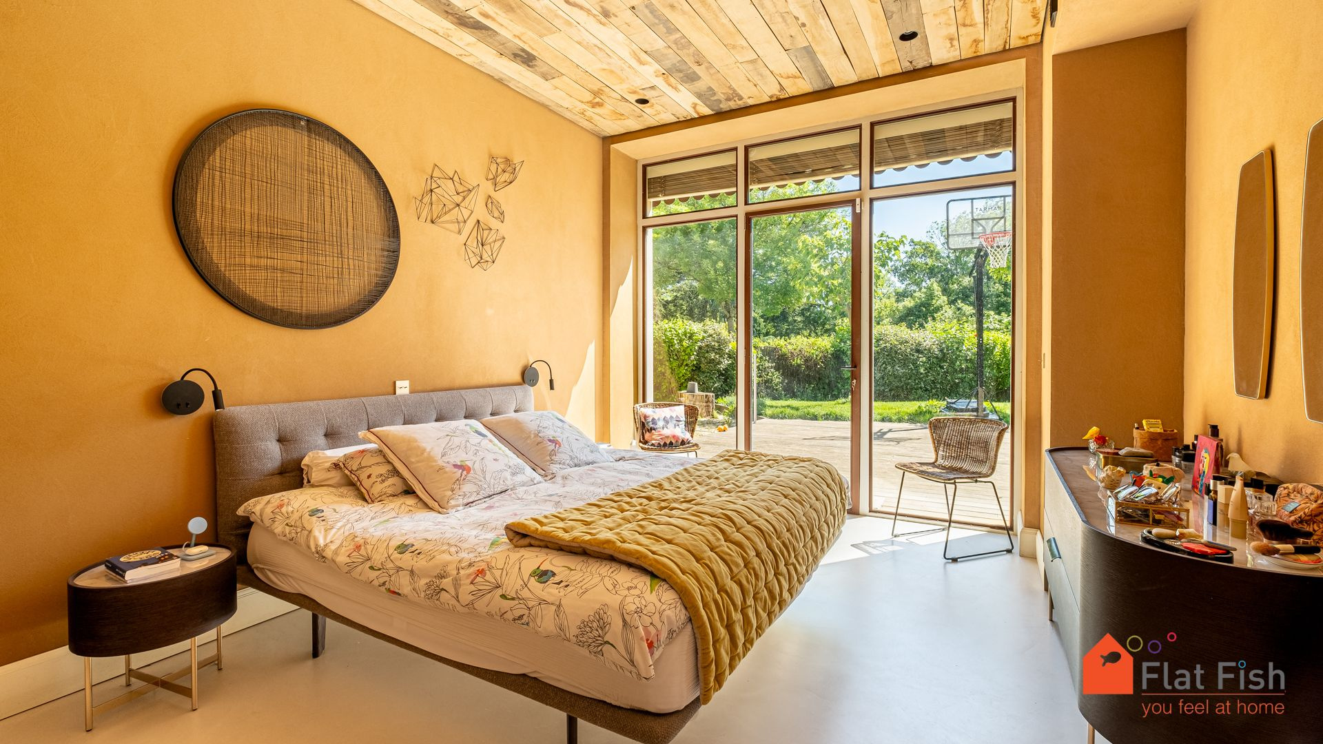 Chambre rénovée avec accès extérieur Chambre spacieuse avec lit double et accès à un jardin, murs en terre cuite et plafond en bois.