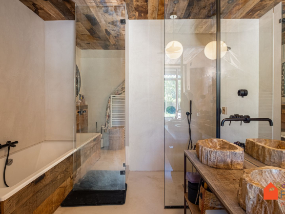 Salle de bains moderne avec baignoire, douche en verre et vasques en bois.