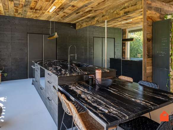 Cuisine moderne avec îlot central en marbre et murs en bois, dans une maison rénovée.