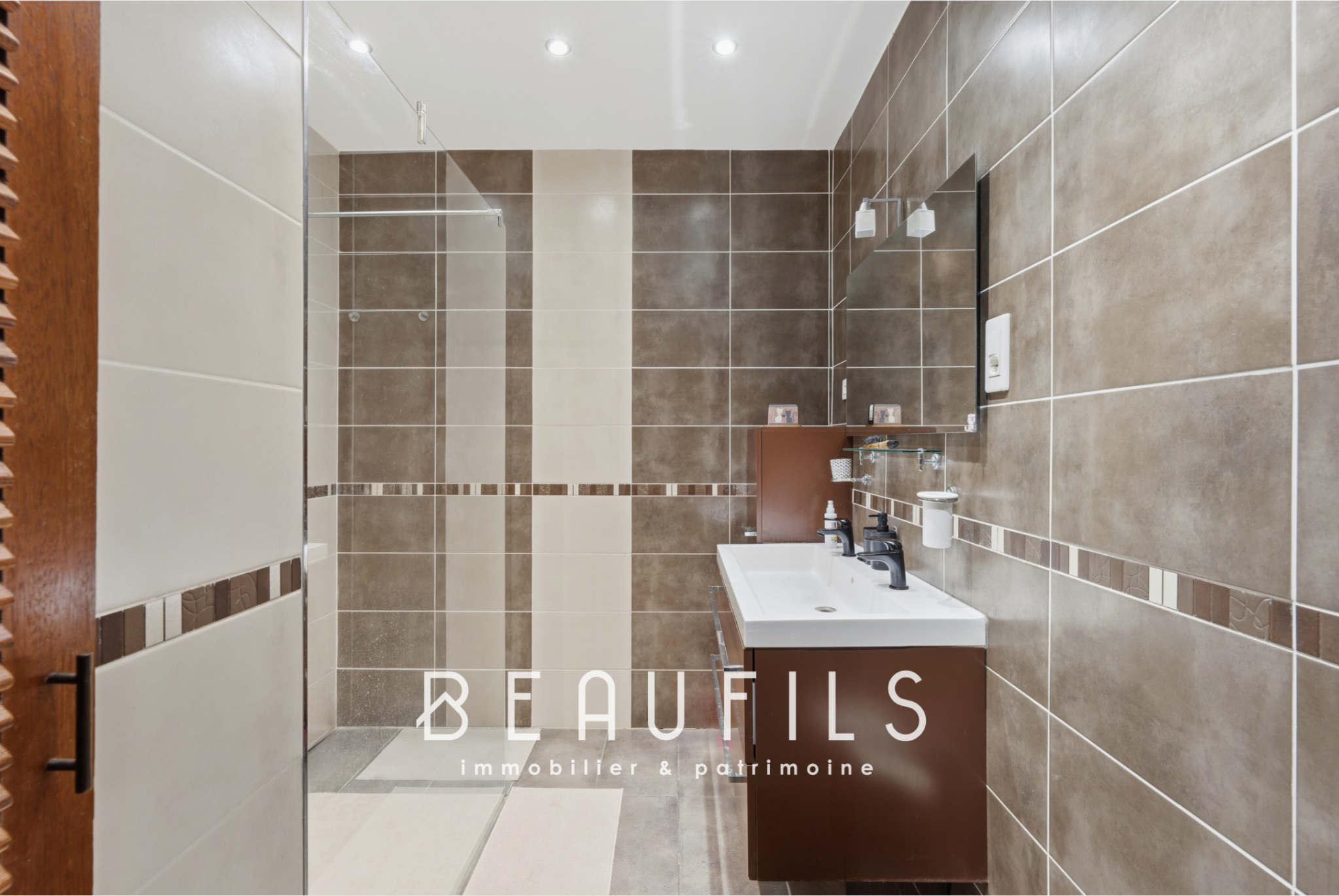 Renovated bathroom Modern bathroom with brown and beige tiled flooring, sink and mirror.