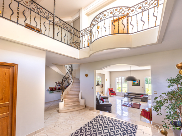 Intérieur d'une villa spacieuse avec escalier en colimaçon et salon lumineux.