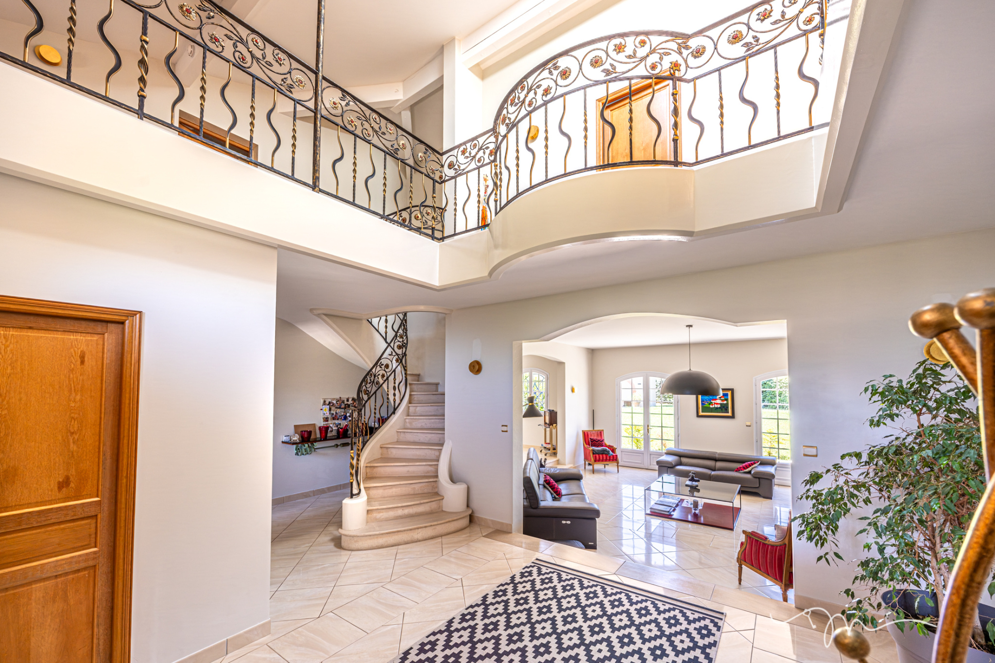 Intérieur d'une villa spacieuse avec escalier en colimaçon et salon lumineux.