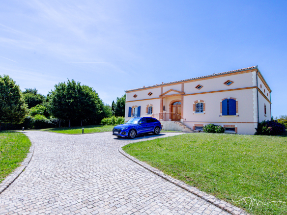 Villa de 335m2 avec piscine et jardin à Préserville, vue extérieure et allée pavée.