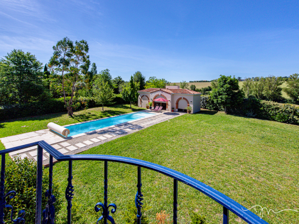 Vue d'ensemble d'une villa avec piscine et jardin à Préserville, entourée d'arbres.
