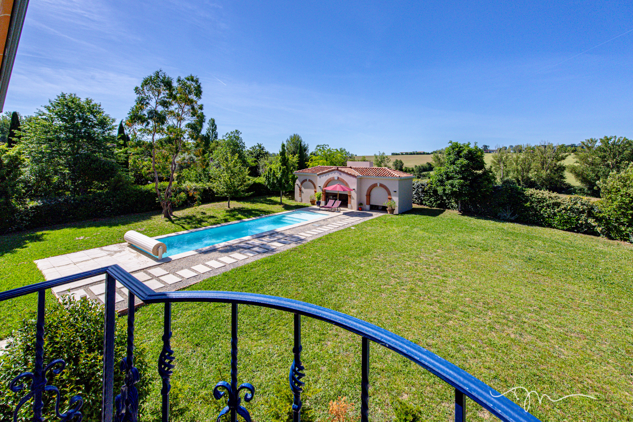 Vue d'ensemble d'une villa avec piscine et jardin à Préserville, entourée d'arbres.