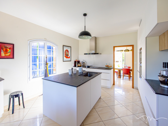 Cuisine moderne avec îlot central et vue sur salle à manger, villa à Préserville.