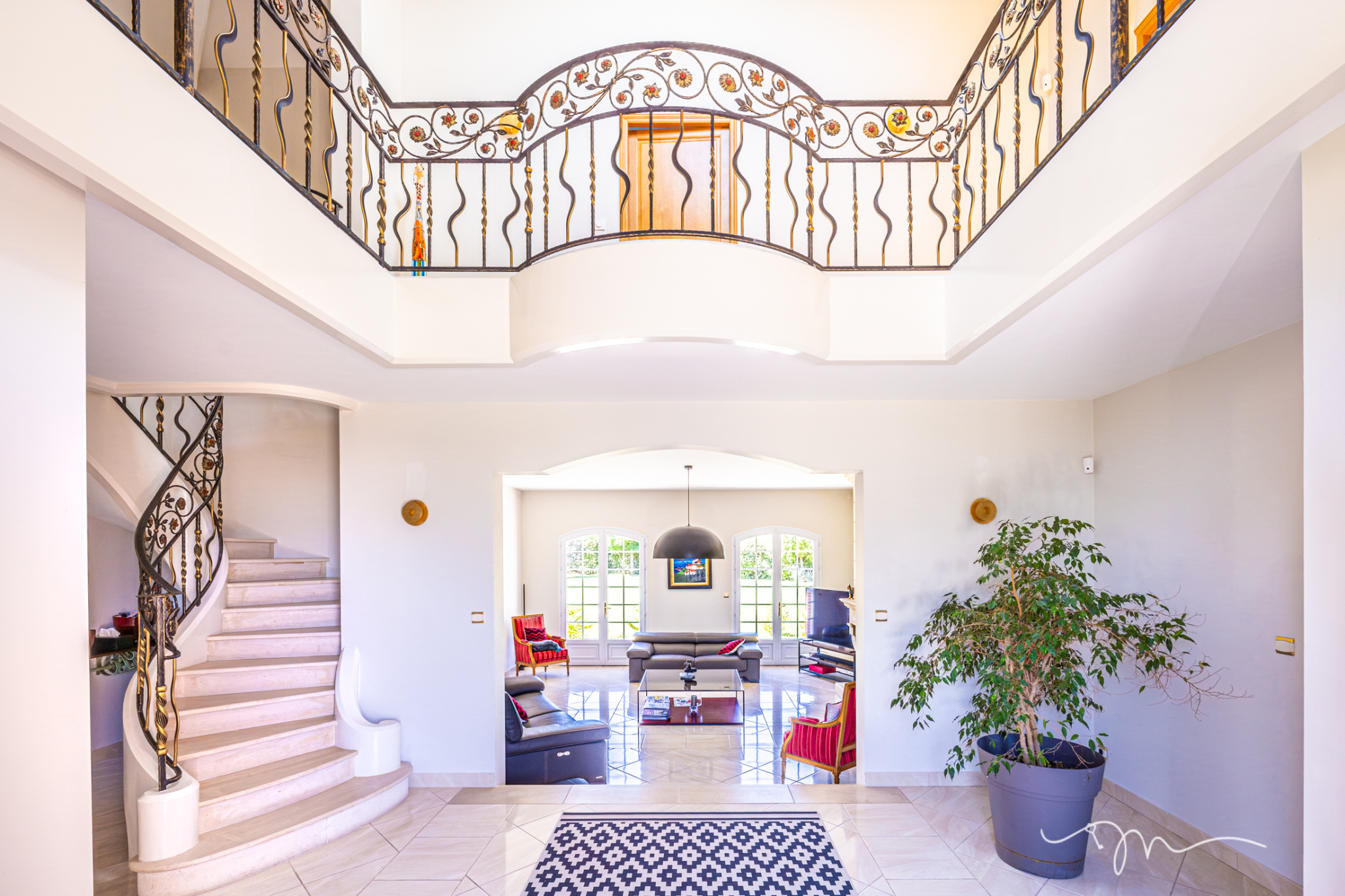 Intérieur d'une villa avec un hall d'entrée spacieux, escalier et salon lumineux.