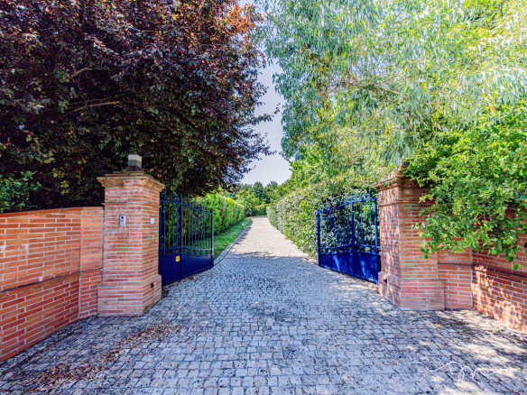 Entrée d'une villa avec portail bleu et chemin pavé, entourée de verdure à Préserville.