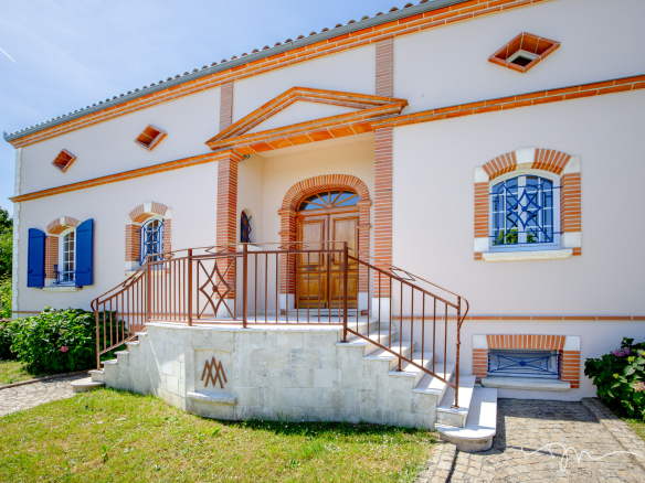 Entrée d'une villa à Préserville avec escalier et jardin fleuri.