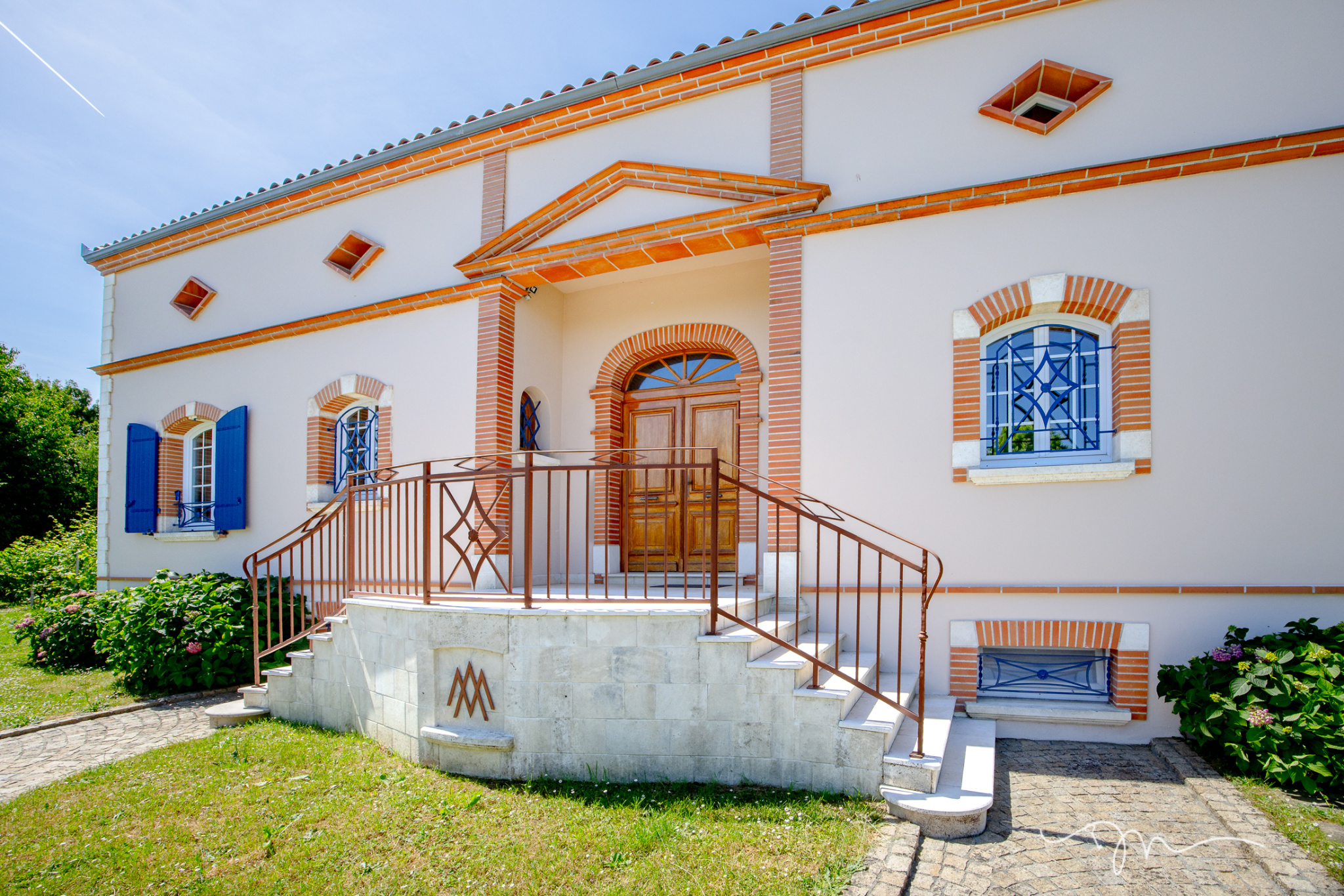 Entrée d'une villa à Préserville avec escalier et jardin fleuri.
