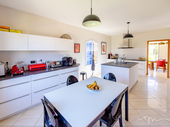 Cuisine moderne et lumineuse d'une villa avec table à manger et équipements électroménagers.