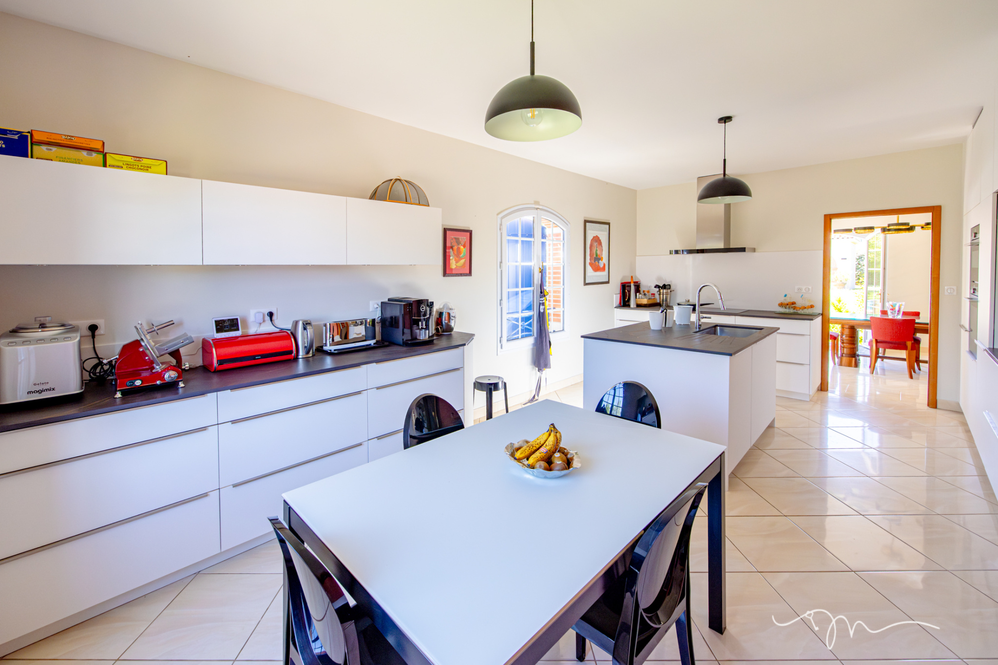 Cuisine moderne et lumineuse d'une villa avec table à manger et équipements électroménagers.