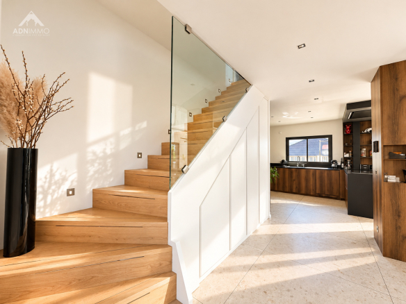 Intérieur d'une maison contemporaine avec un escalier en bois et une cuisine moderne.