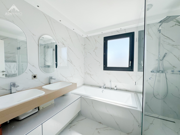Salle de bain moderne avec baignoire et douche, murs en marbre, lumière naturelle