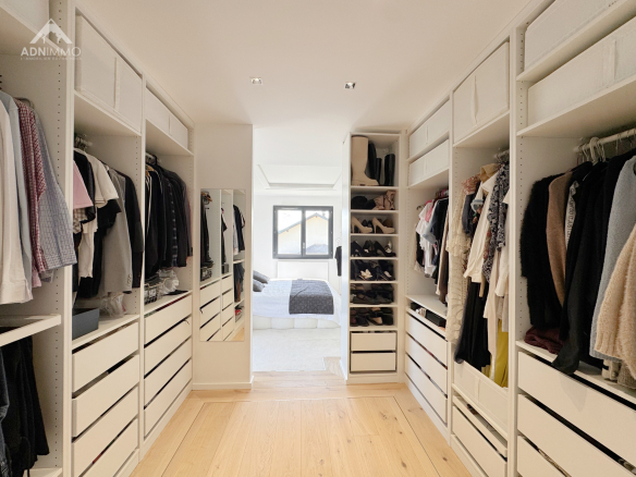 Intérieur d'un dressing spacieux avec des rangements pour vêtements et chaussures.
