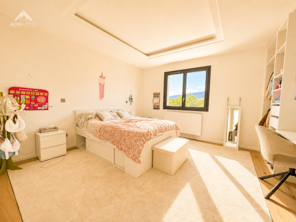 Chambre lumineuse d'une maison contemporaine avec lit et bureau, située à Saint-Genis-Pouilly.