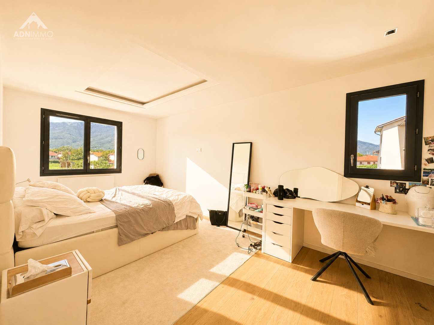 Chambre moderne et lumineuse Chambre lumineuse avec lit, bureau et fenêtres sur un paysage montagneux.