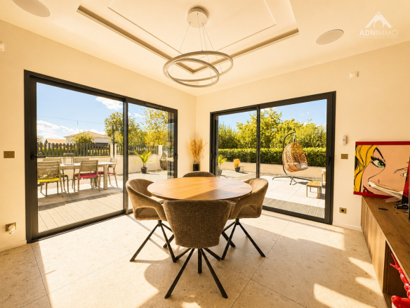 Intérieur d'une maison contemporaine avec une salle à manger lumineuse et vue sur l'extérieur.