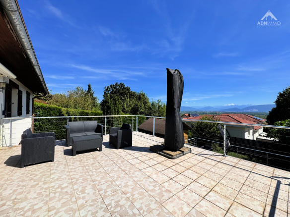 Terrasse d'une maison à Crozet avec mobilier de jardin et vue sur les Alpes.
