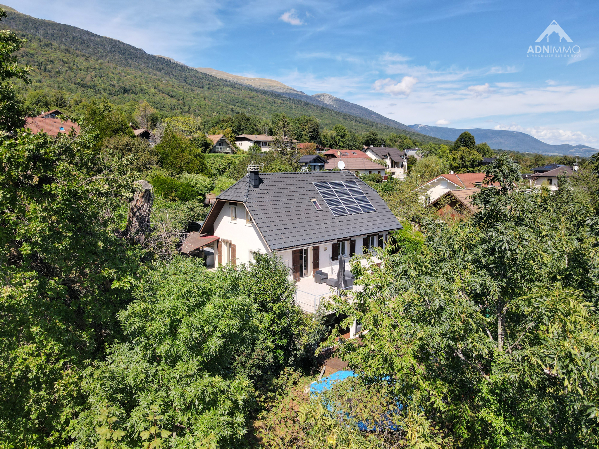Maison individuelle entourée d'arbres à Crozet, avec vue sur les montagnes et le Mont-Blanc.