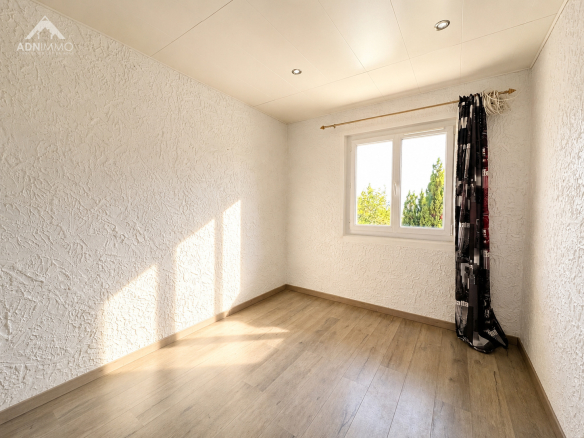 Intérieur d'une chambre lumineuse avec fenêtre et rideaux à Crozet.