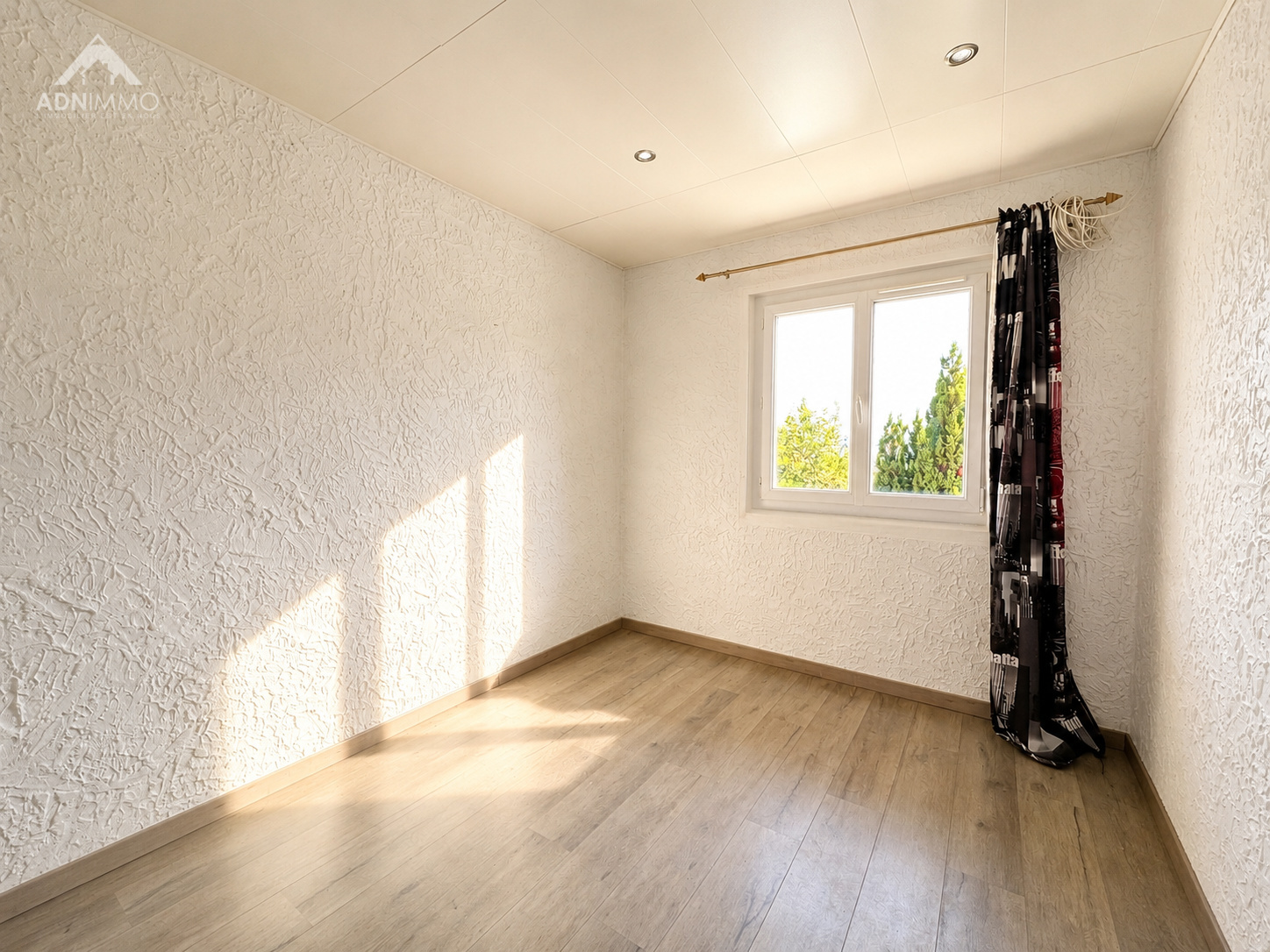 Intérieur d'une chambre lumineuse avec fenêtre et rideaux à Crozet.