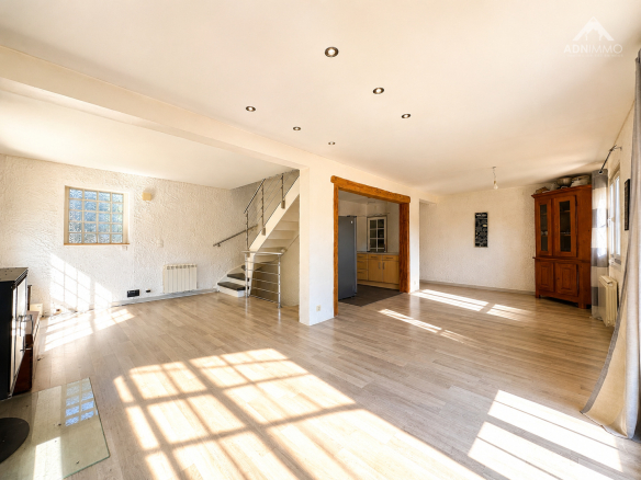 Intérieur lumineux d'une maison spacieuse avec un grand salon et des fenêtres laissant entrer la lumière.